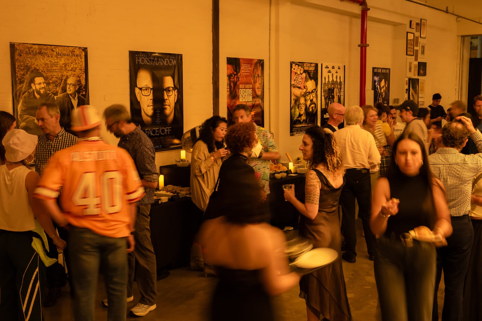 A crowded view of the Macktez office packed with party guests, string lights and candles lit throughout the room
