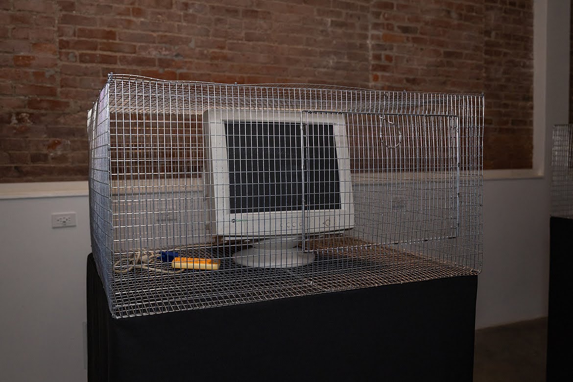 Wire cage containing an old CRT computer monitor, part of the tech beast installation