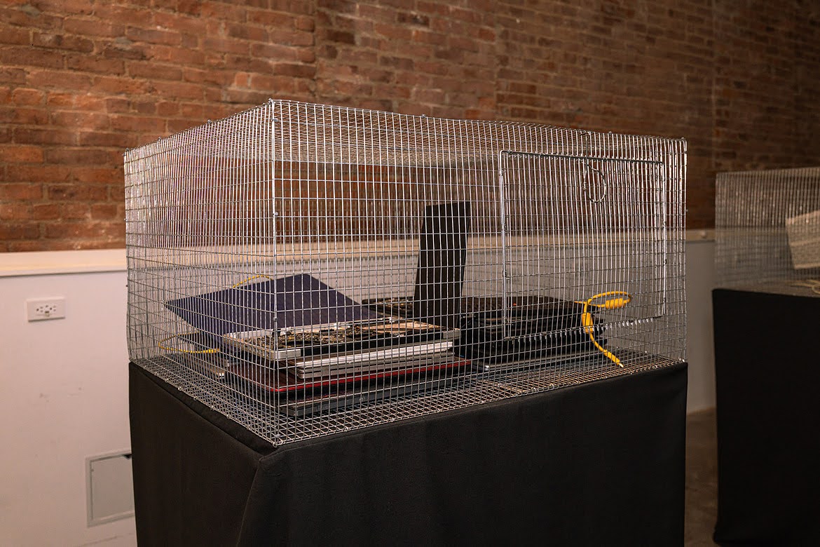Wire cage containing a disassembled laptop motherboard and components