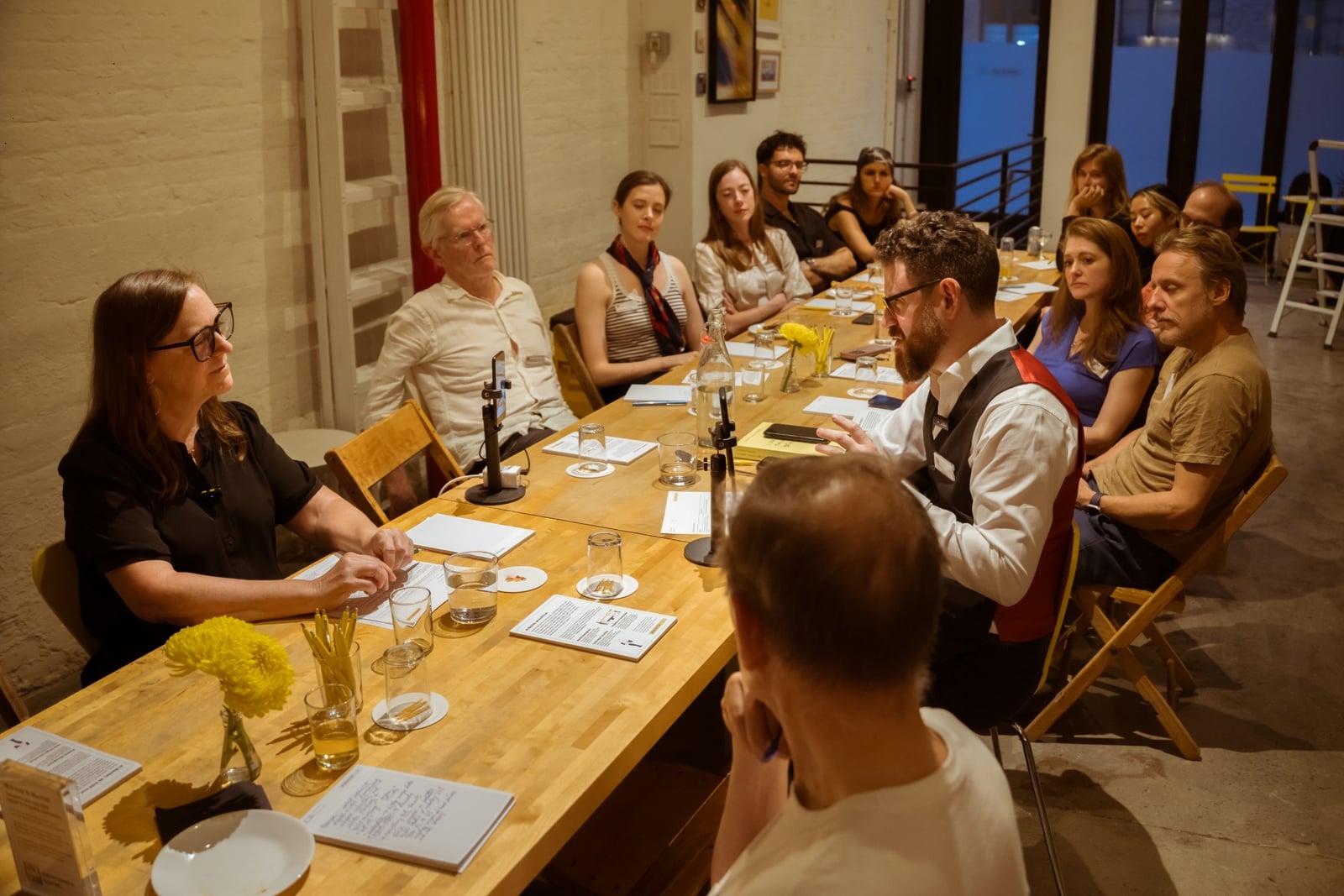 Attendees seated around the long table during the Tête-à-Tech discussion, listening to Francine Snyder