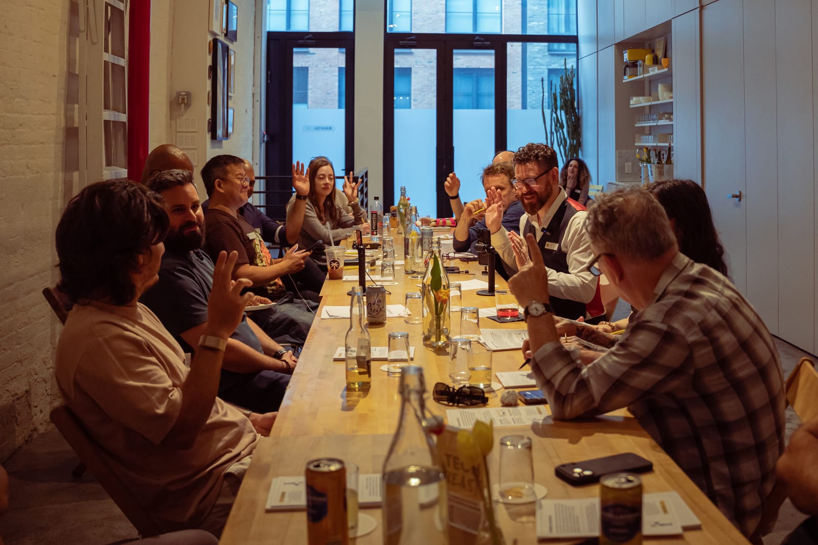 Attendees seated around a long table during the Tête-à-Tech discussion, several with hands raised